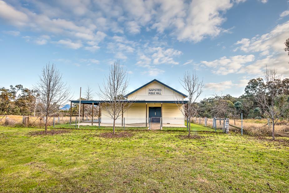 The exterior of Gapsted Public Hall, a white weatherboard single-story building with a peaked roof and green trim.