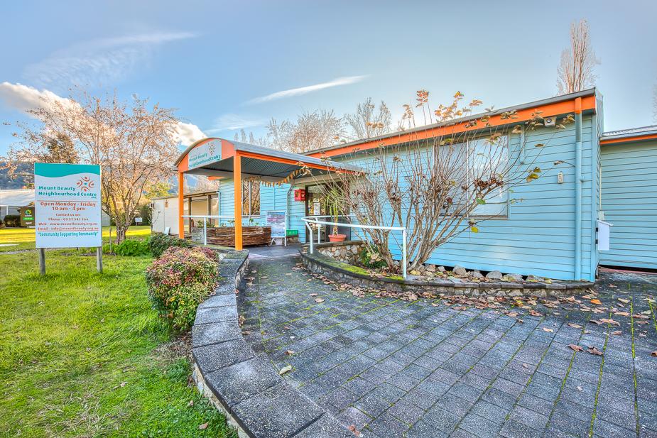 Exterior of the Mount Beauty Neighbourhood Centre, clad in a cream weatherboard with light blue trim.
