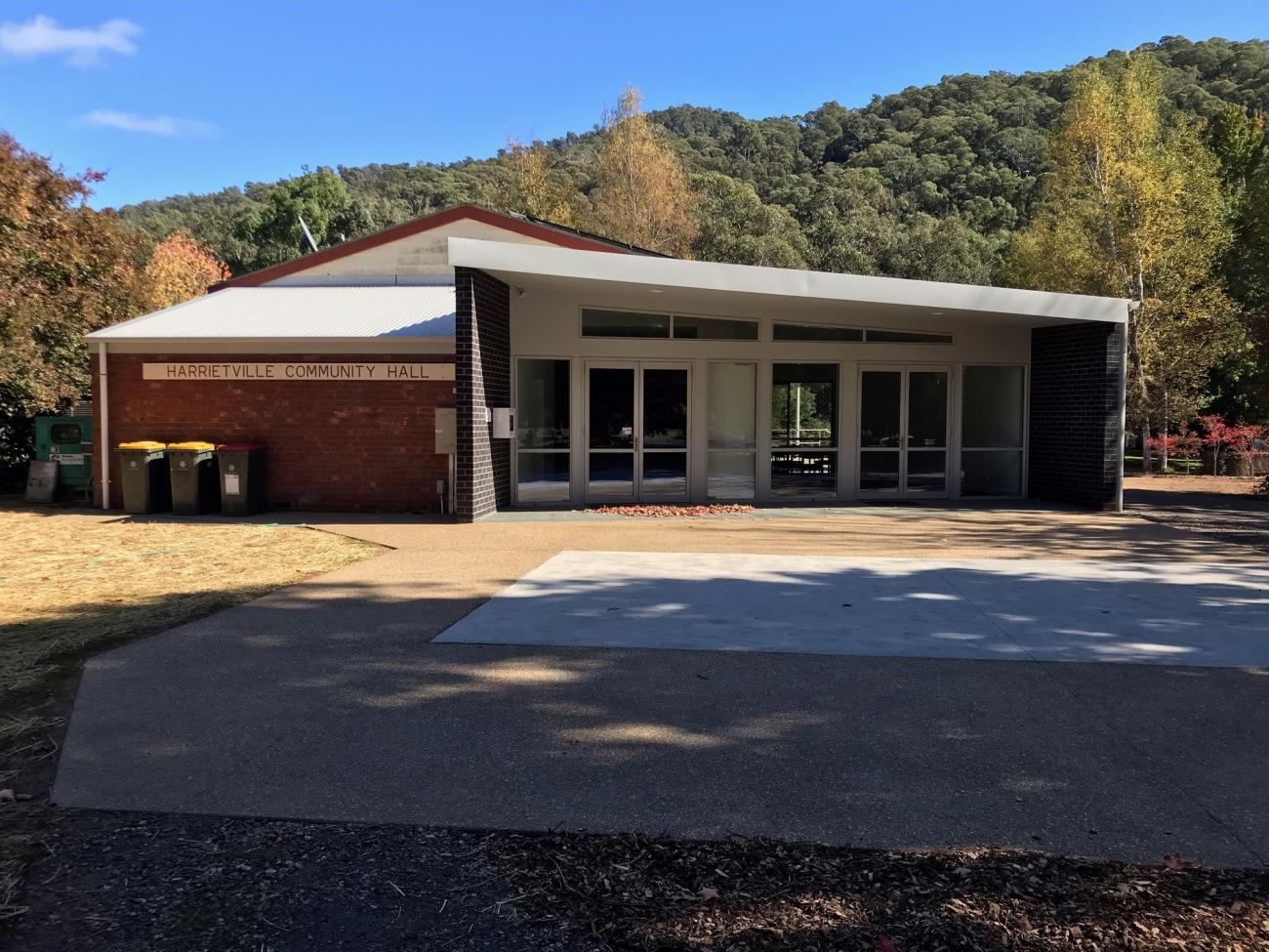 The exterior of Harrietville Community Hall, with a red brick exterior and glass windows.