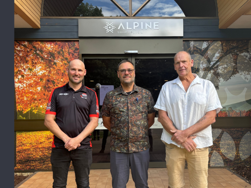 Three men stand in front of the Council office in Bright, smiling at the camera.