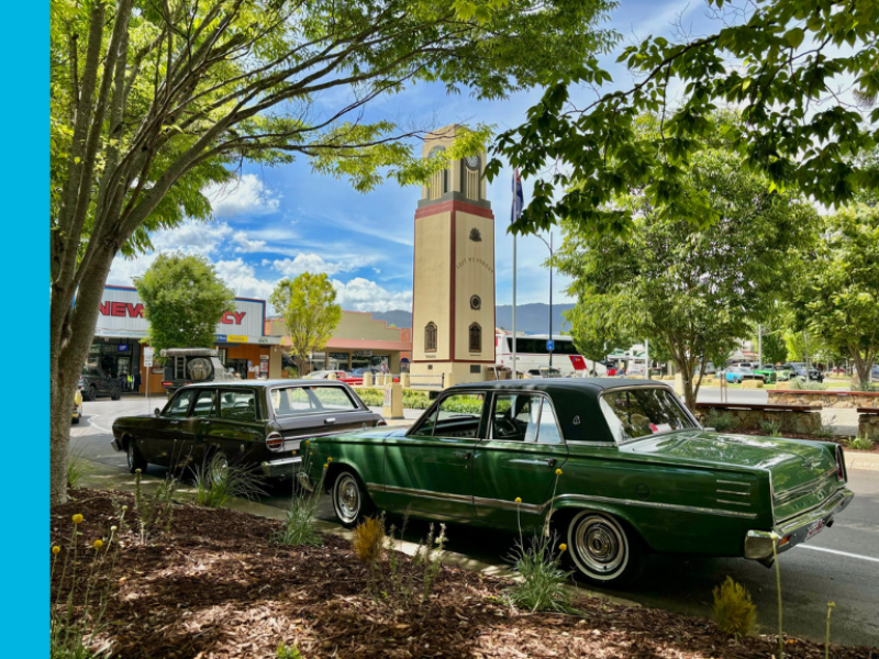 Two heritage cars moving around a memorial roundabout with a clocktower in the centre.