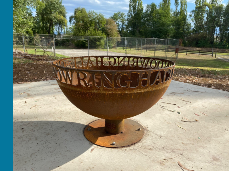 A round, iron fire pit with the words Gundowring Hall cut into the iron.