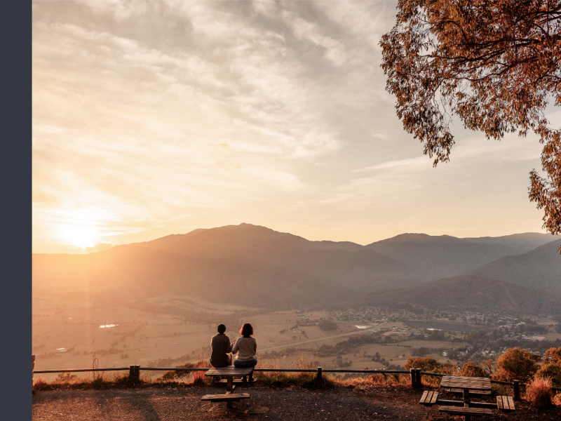 Two people look out at a sunrise over Mount Emu and Bogong from Sullivan's Lookout.