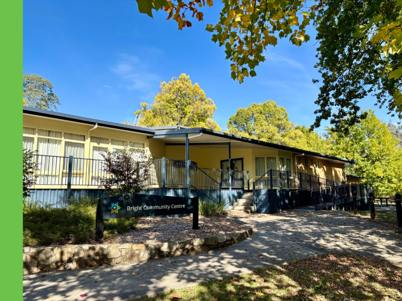 An exterior shot of Bright Community Centre, a community building with yellow weatherboard, a blue deck, and blue guttering.