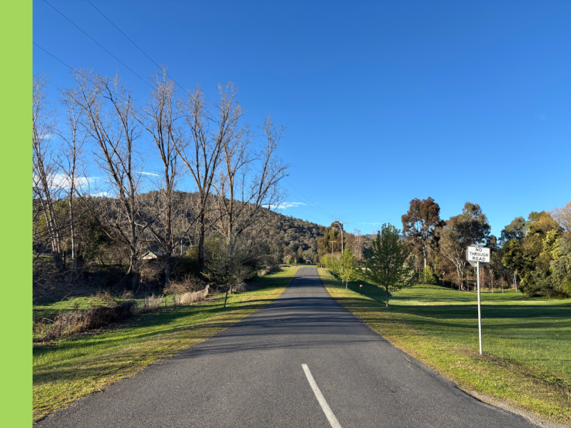 A bitumen road with green grass on either side. There is a sign on the right side that says No Through Road.