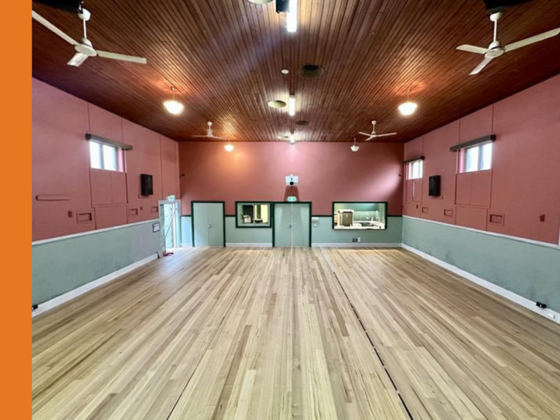 A hall with blonde timber flooring and walls painted mint green along the bottom and maroon along the top.