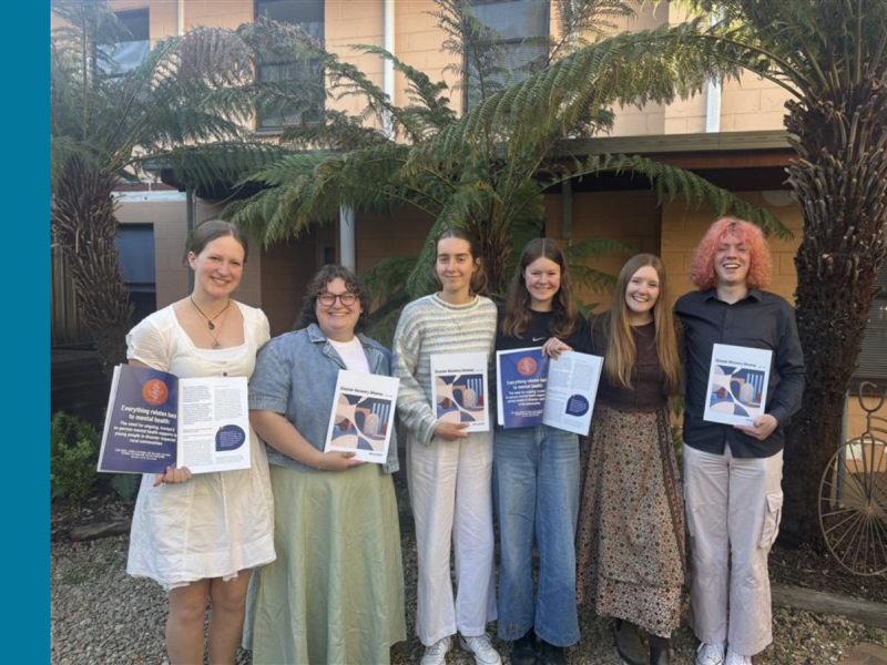 Six young people stand in a row, looking at the camera and holding a copy of the 2025 Disaster Recovery Almanac, an A4 book.