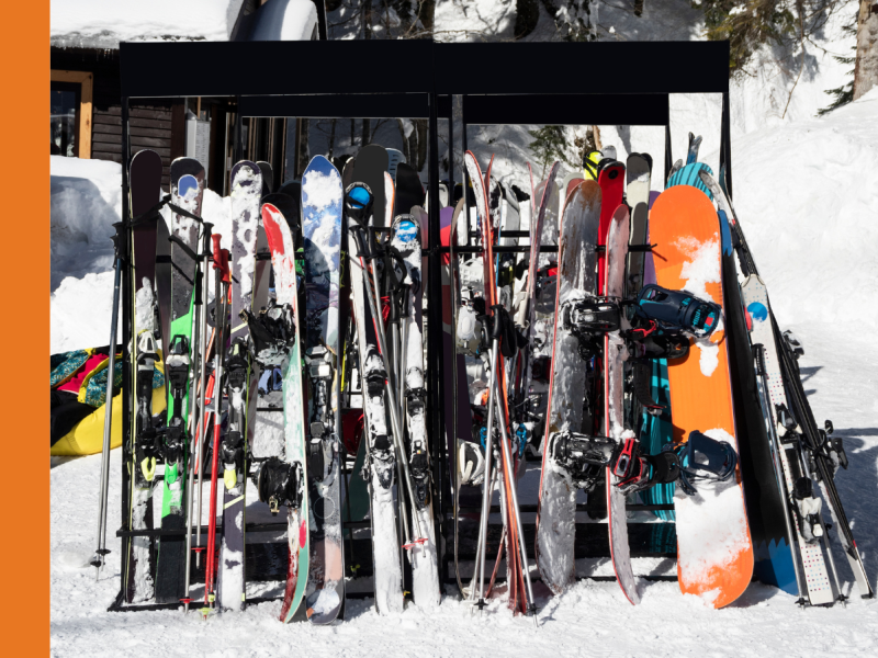 Skis and snowboards leaning against a rack at the snow.