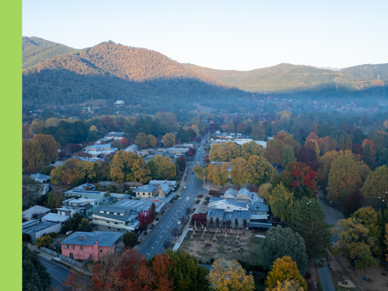 An overhead image of a town with a main street lined by shopfronts and small mountains in the background.