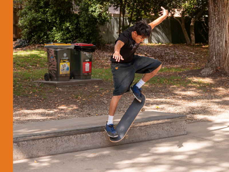 A young man grinds a skateboard along a concrete block in a skate park.
