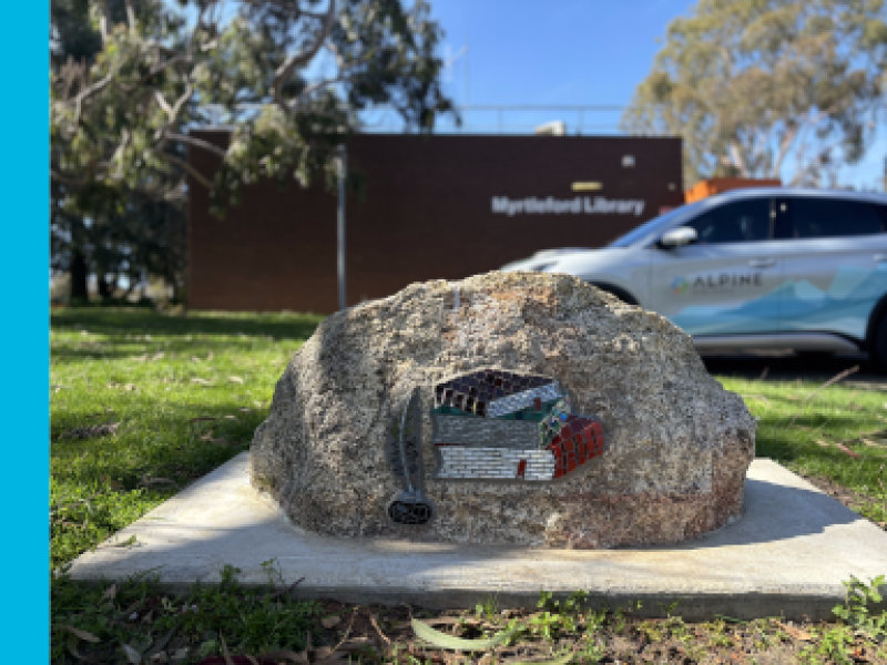 A rock with a stack of mosaic books on it.