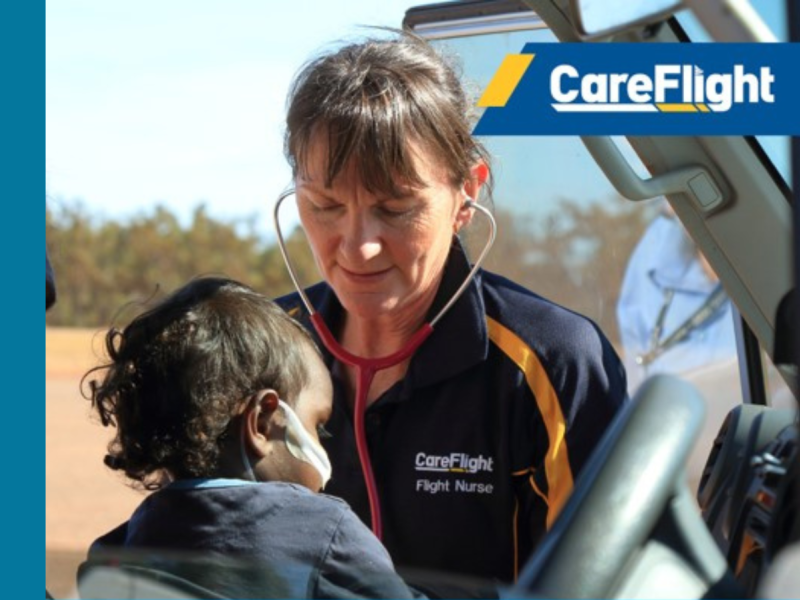 A CareFlight flight nurse leans into a vehicle doorway while attending to a young child who is seated inside and wearing medical tubing. The child is held by an adult seated in the vehicle. The CareFlight logo appears in the upper right corner of the image.
