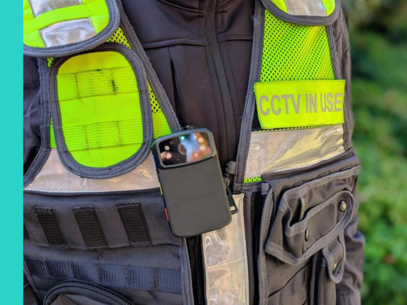 A close up view of a Ranger black, silver and yellow reflective vest with a body camera positioned in the centre of the vest, and a badge with the words 'CCTV IN USE' on the breast of the vest.
