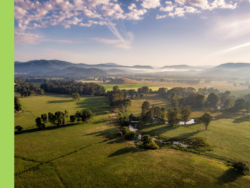 A landscape vista with green fields and hills in the distance. The blue sky is streaky with clouds.