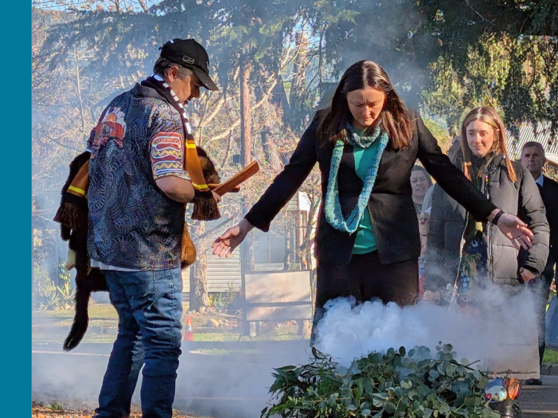 A woman participates in a smoking ceremony led by an Aboriginal Elder.