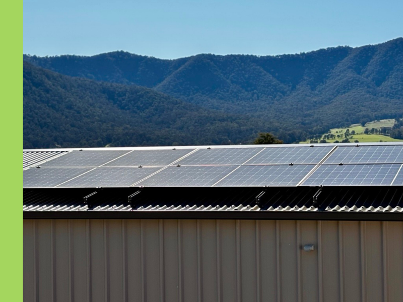 A roof with solar panels on it. There are hills in the background.
