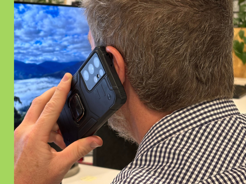 A man with a collared shirt on holds a mobile phone up to his ear. He is facing away.