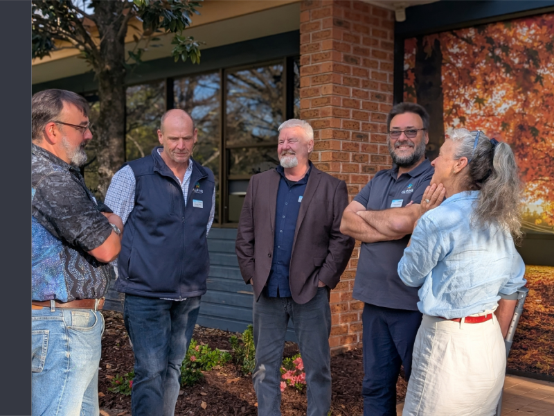Four men and one woman stand together, laughing.