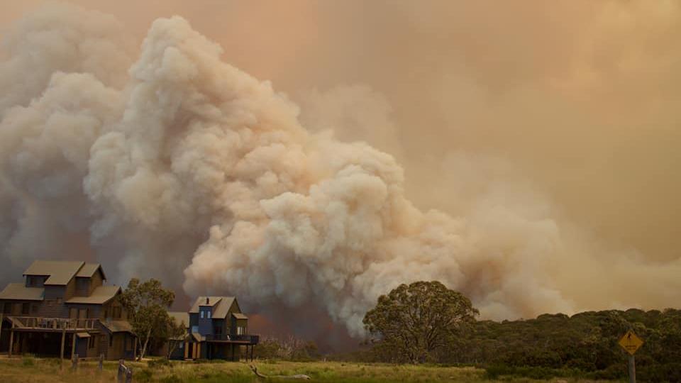 A massive cloud of bushfire smoke rises behind houses in Dinner Plain.