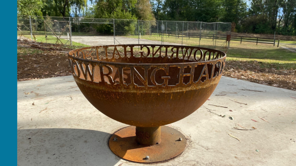 A round, iron fire pit with the words Gundowring Hall cut into the iron.