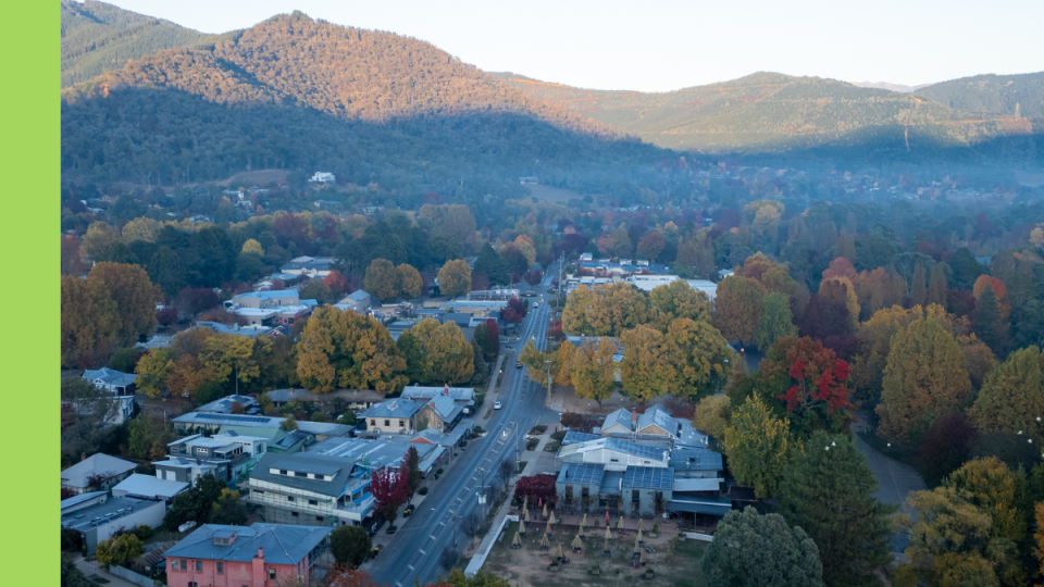 An overhead image of a town with a main street lined by shopfronts and small mountains in the background.