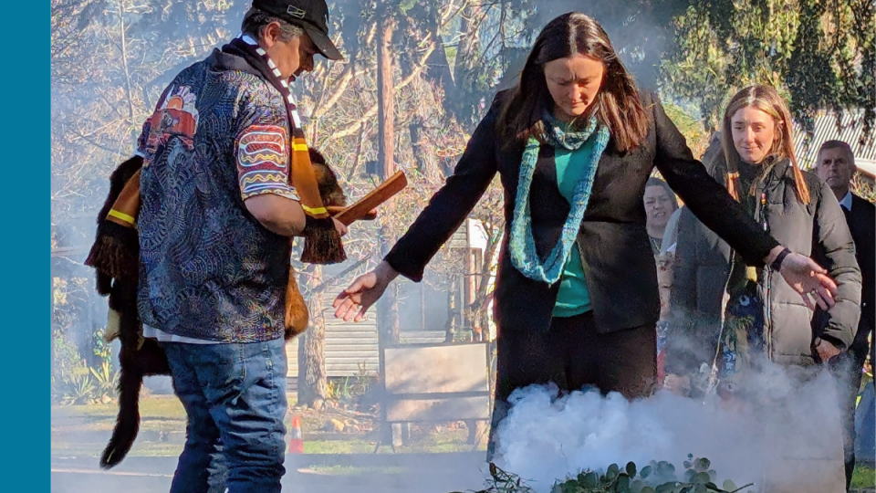 A woman participates in a smoking ceremony led by an Aboriginal Elder.
